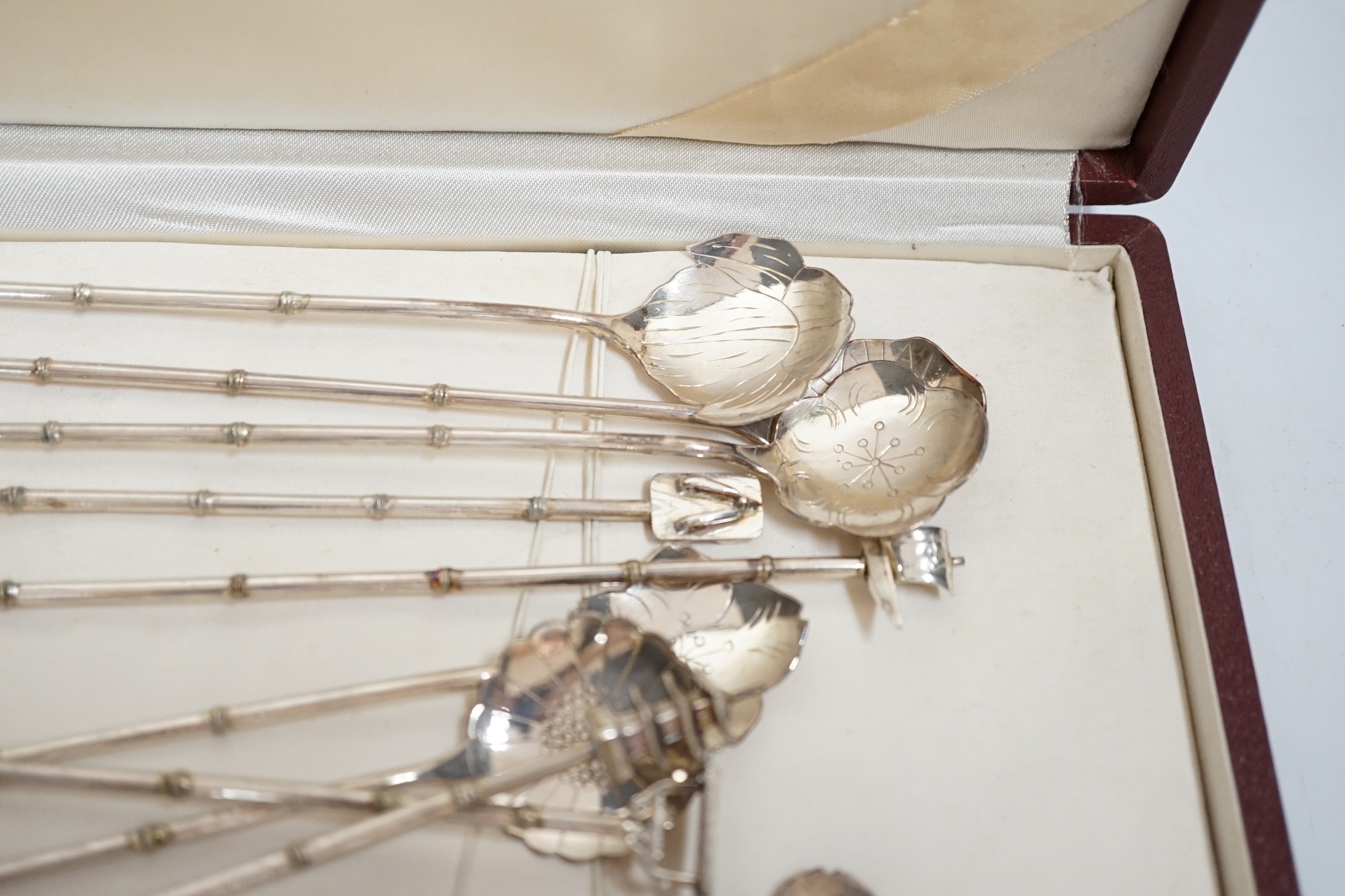 A cased set of twelve Japanese? white metal cocktail spoon, with differing terminals, 21.1cm.